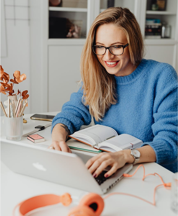 امرأة ترتدي نظارات تعمل على لابتوب في مساحة عمل حديثة